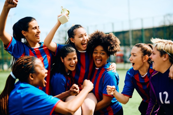 a team of female athletes celebrate on the field after winning a trophy